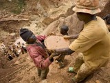 Gold miners form a human chain while digging an open pit in northeastern Congo